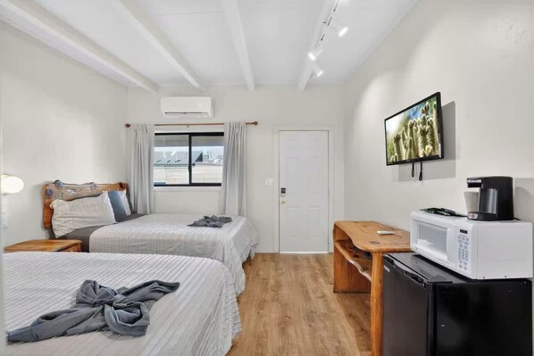 A hotel room with two beds, a wooden desk, a microwave, and a television. - Highlander Room 4 Cozy Private Room in Williams (Williams)