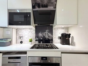 A modern kitchen with a stainless steel range, a microwave, and a dishwasher. - Tower Bridge Stay | 2 Bed | Fast WiFi & Parking (Greater London)