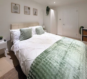 A bedroom with a bed, bedside table, and a door. - Tower Bridge Stay | 2 Bed | Fast WiFi & Parking (Greater London)