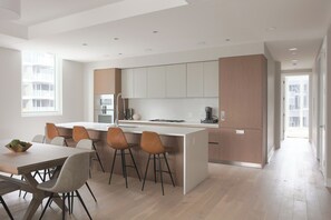 A modern kitchen with a central island, bar stools, and a dining table with chairs. - Luxury Loft Collection COMBO 901/902 | Terrace (Chicago)