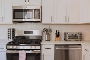A kitchen with white cabinets, a stainless steel stove, a microwave, a toaster, and a dishwasher. - Designer Combo Loft 3E & 3W|GoldCoast/River North (Chicago)