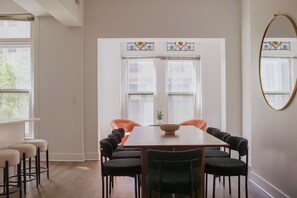 A dining area with a rectangular table, multiple chairs, and a window with stained glass. - Designer Combo Loft 3E & 3W|GoldCoast/River North (Chicago)