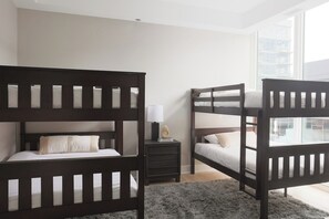 A bedroom with two bunk beds, a bedside table with a lamp, and a view of a building through a window. - Luxury Loft Collection COMBO 901/903 | Terrace (Chicago)
