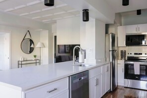 A modern kitchen with white cabinetry, stainless steel appliances, and a central island with a sink. - Luxury Designer COMBO 802/803| Gold Coast/Old Town (Chicago)