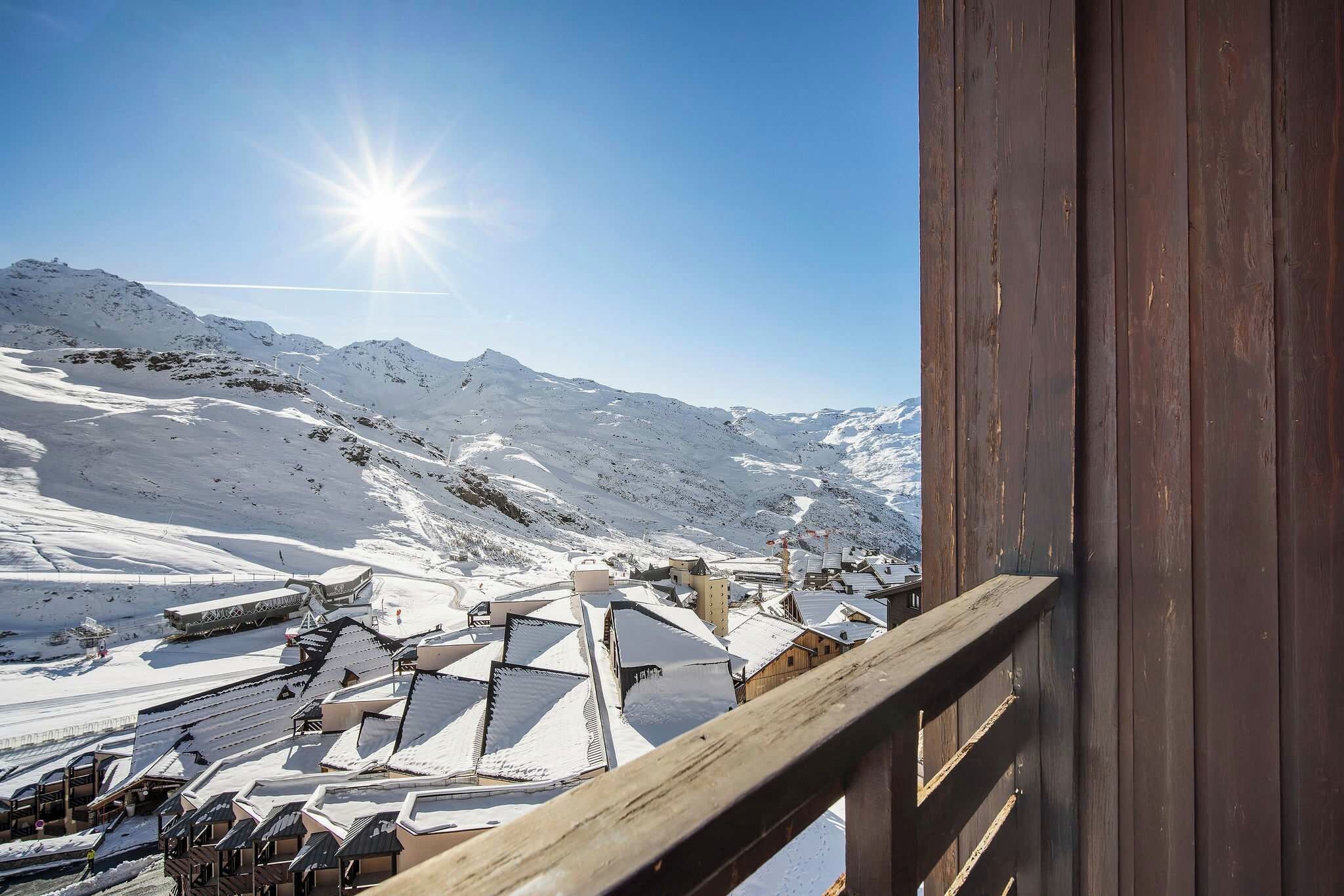 Un paysage de montagne enneigé avec un bâtiment en bois et un télésiège en arrière-plan.