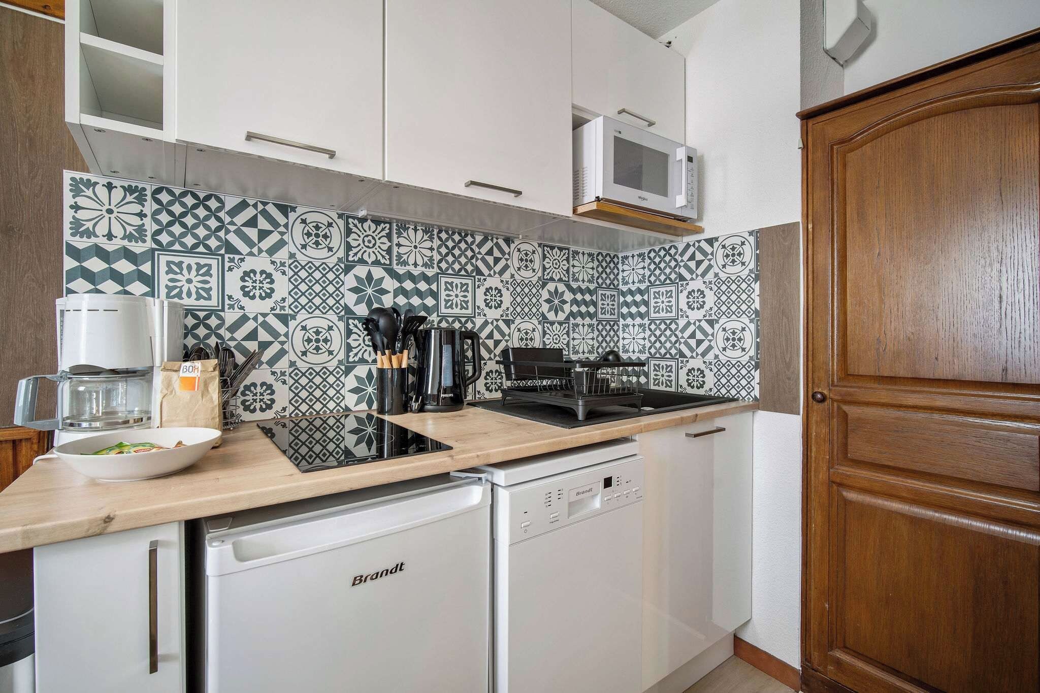 Una cocina con lavavajillas blanco, microondas y un armario de madera.