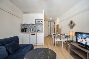 A compact living space with a kitchenette, a dining area, and a seating area with a TV.