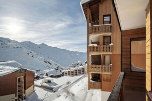 A wooden chalet with balconies overlooking a snowy mountain landscape.