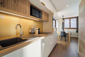 A modern kitchen with a built-in microwave, stainless steel sink, and wooden cabinets.