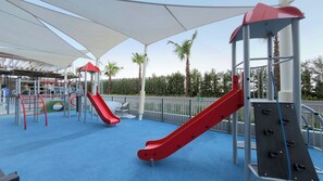 A children's play area with slides and climbing structures. - Rentico | Resort Studio | Pool, Sauna, Gym, BBQ (Dubai)