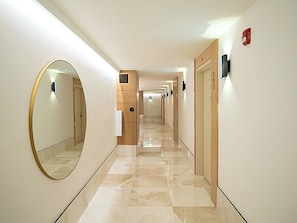 Passadís d'hotel amb un mirall, portes i un detector de fum.