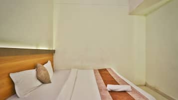 Habitación de hotel con cama, almohadas, cabecera de madera y toalla.