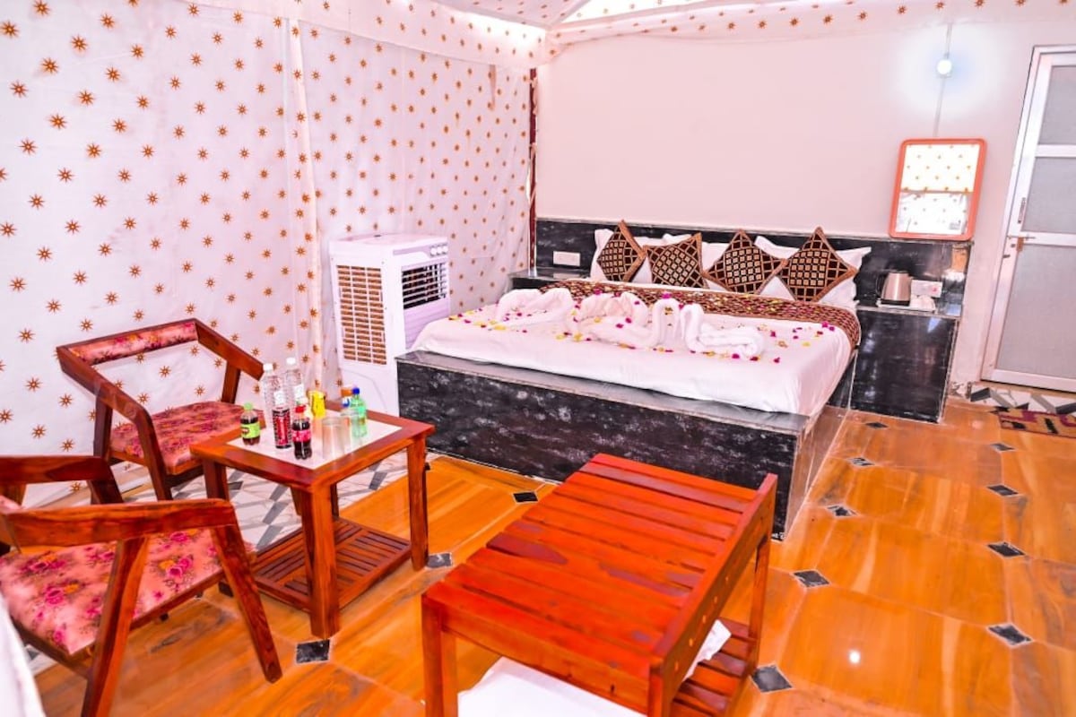 Quarto de hotel com cama, mesa e cadeiras, ar condicionado e piso ladrilhado.