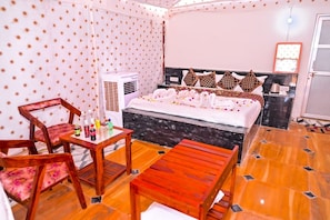 Quarto de hotel com cama, mesa e cadeiras, ar condicionado e piso ladrilhado.