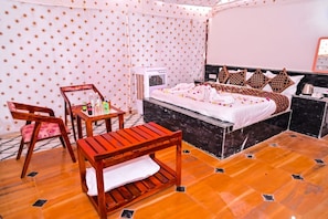 Quarto de hotel com cama, uma mesinha, uma cadeira e ar condicionado.