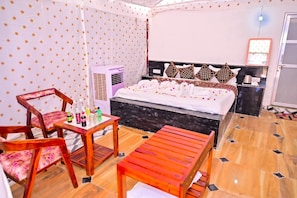 Een hotelkamer met een bed, een tafel met stoelen, een airconditioner en een spiegel aan de muur.