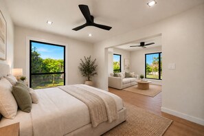Ein modernes Schlafzimmer mit einem großen Bett, einer Couch, einem Couchtisch und einem Deckenventilator.