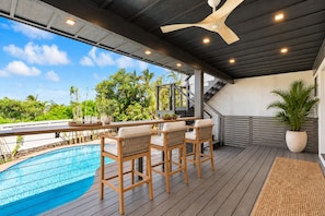 Ein überdachter Außenbereich mit Pool, Holzterrasse und Sitzgelegenheiten.