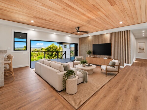 Ein modernes Wohnzimmer mit einem großen Sofa, einem Couchtisch und einem an einer Holzwand montierten Fernseher.