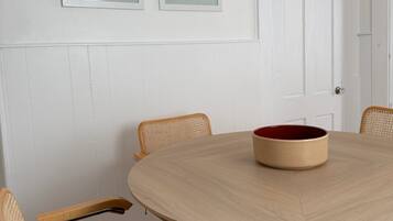 Een eetgedeelte met een ronde tafel, stoelen en twee ingelijste kunstwerken aan de wand.