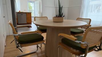 En matplats med ett runt bord, fyra stolar med gröna kuddar och en krukväxt på bordet.
