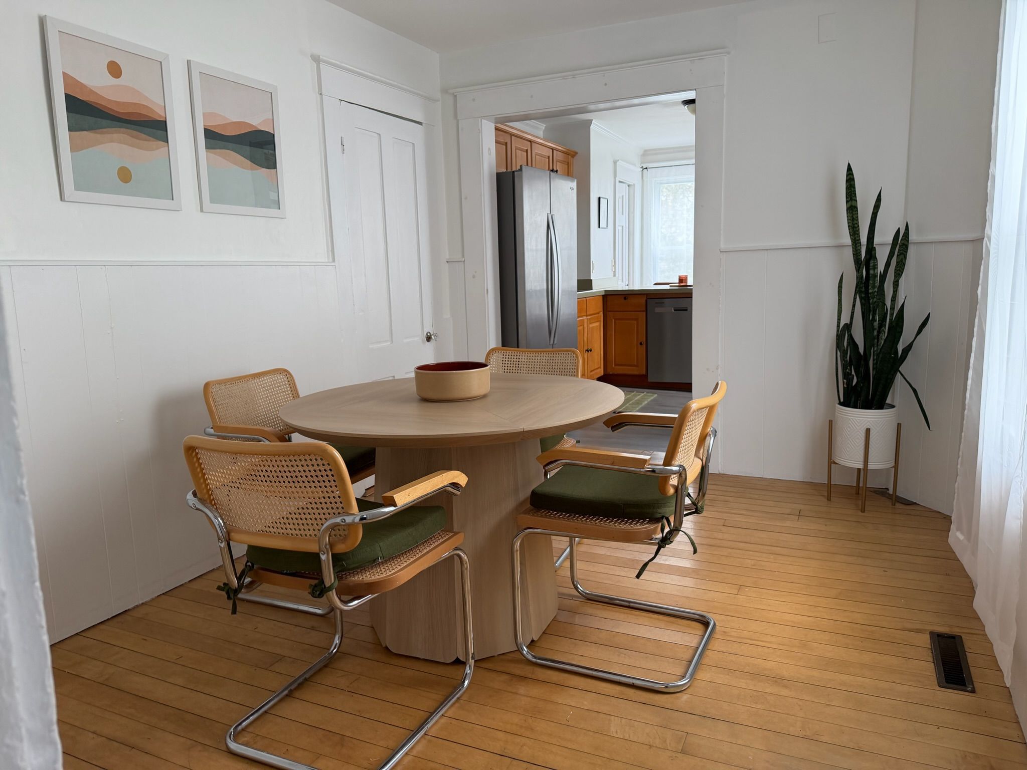 En matplats med ett runt bord, sex stolar och utsikt in i köket.