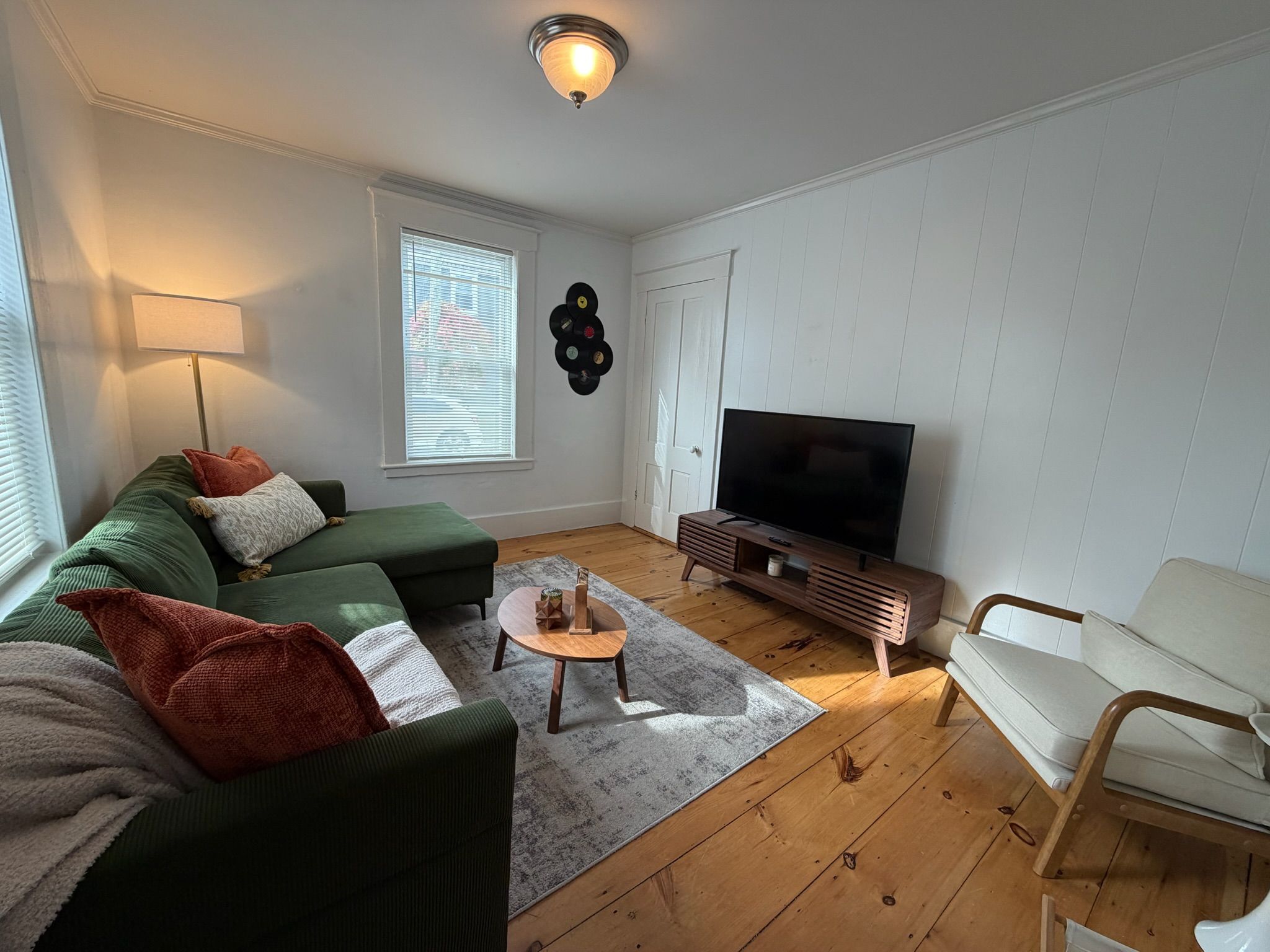 Ett vardagsrum med en soffa, ett soffbord, en tv och en fåtölj.