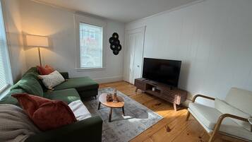 Ett vardagsrum med en soffa, ett soffbord, en tv och en fåtölj.