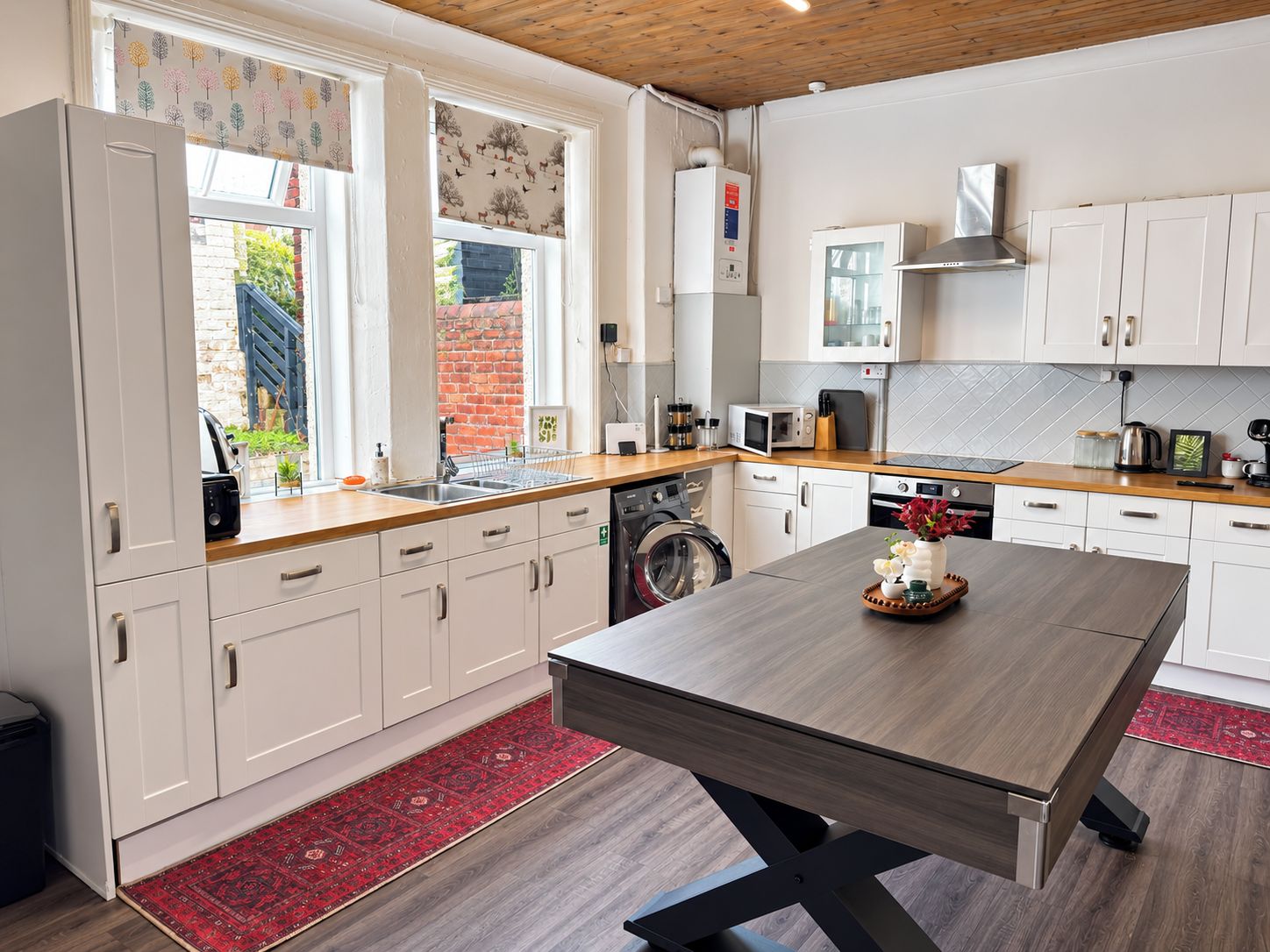 Et moderne køkken med hvide skabe, en træbordplade og en central køkkenø.