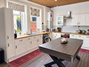 Et moderne køkken med hvide skabe, en træbordplade og en central køkkenø.