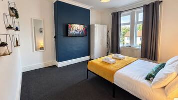 Ein Hotelzimmer mit Bett, Flachbildfernseher, Kleiderschrank und einem fenster mit Vorhängen.