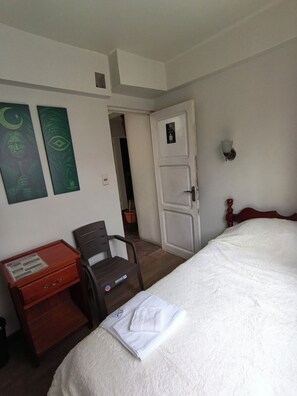 A hotel room with a bed, a desk with a chair, and two wall art pieces. - Hostal Kalopsia Suites (La Paz)