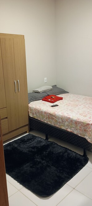 Ein kleines Schlafzimmer mit einem Bett, einem Kleiderschrank und einem schwarzen Teppich.