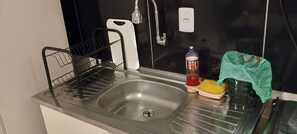 A stainless steel sink with a dish rack, a bottle of hand soap, and a sponge.