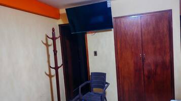 A room with a bed, a chair, a wardrobe, and a television.