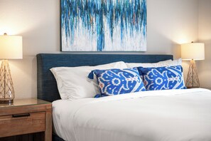 A hotel room with a bed, two bedside lamps, a nightstand, and a painting on the wall. - Naples Duo 1 | 2 Homes • Pools • King Beds (Naples)