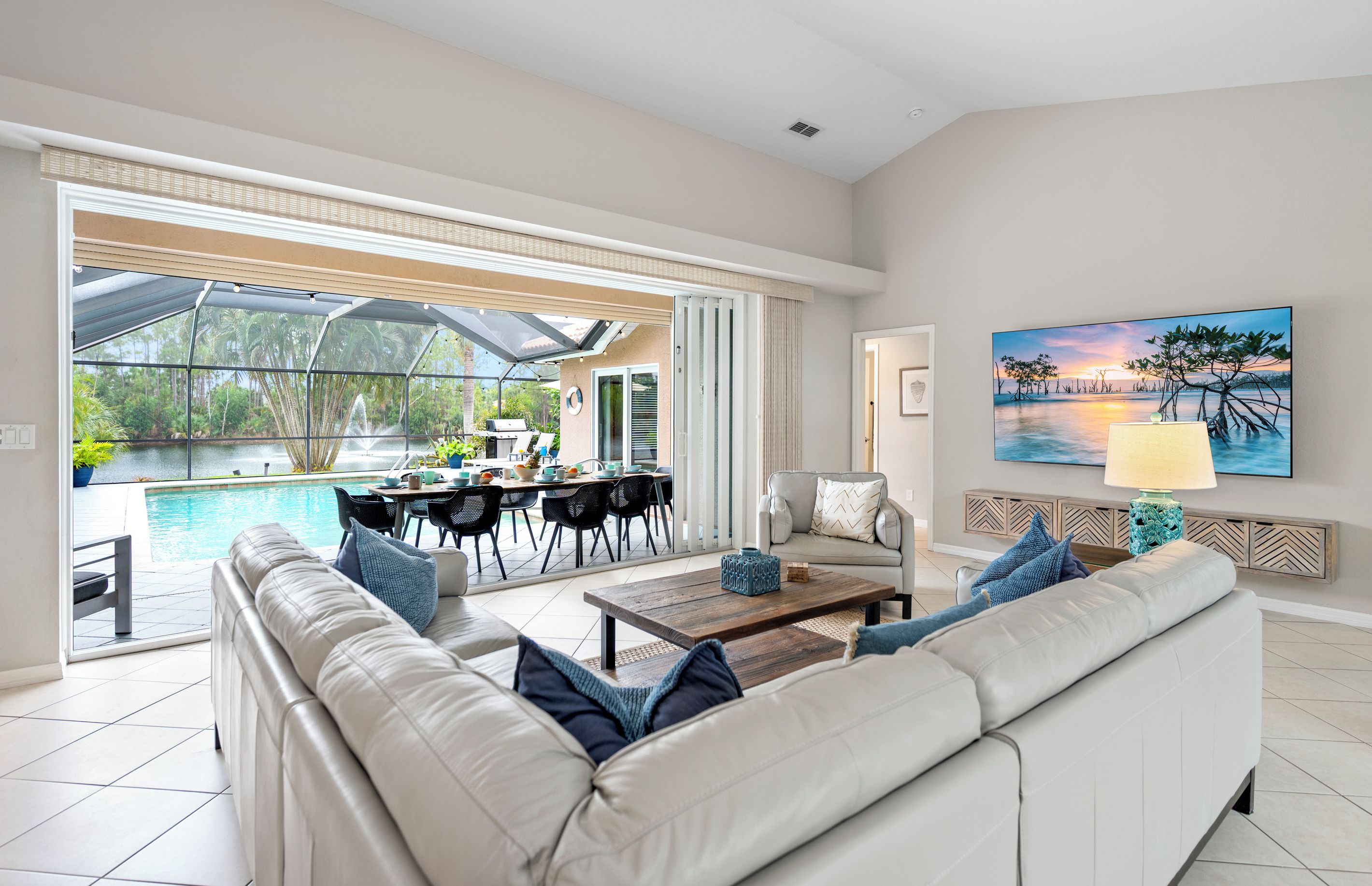 A modern living room with a pool view, a dining area, and a painting on the wall.