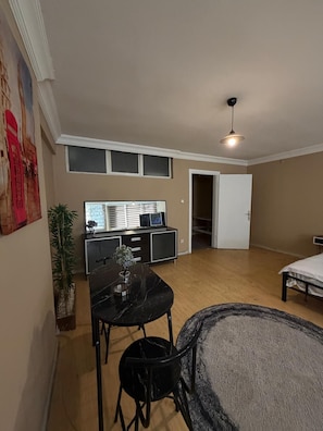 A spacious room with a dining table, chairs, a sofa, a TV, and a door leading to another room. - Cozy 1-bedroom Apartment in Pendik, Türkiye (Istanbul)