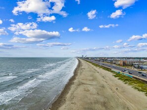 Eine Küstenstraße mit Strand auf einer Seite und Gebäuden auf der anderen.