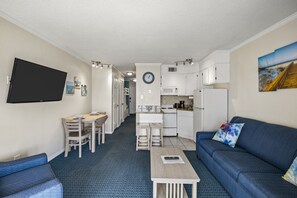 Ein kompakter Wohnraum mit Küchenzeile, Essbereich, Sofa und Flachbildfernseher.