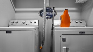 A laundry room with two Maytag washing machines, a towel rack, and a bottle of orange liquid. - Salty Pelican | Easy Beach Access | Fenced Yard (Bolivar Peninsula)