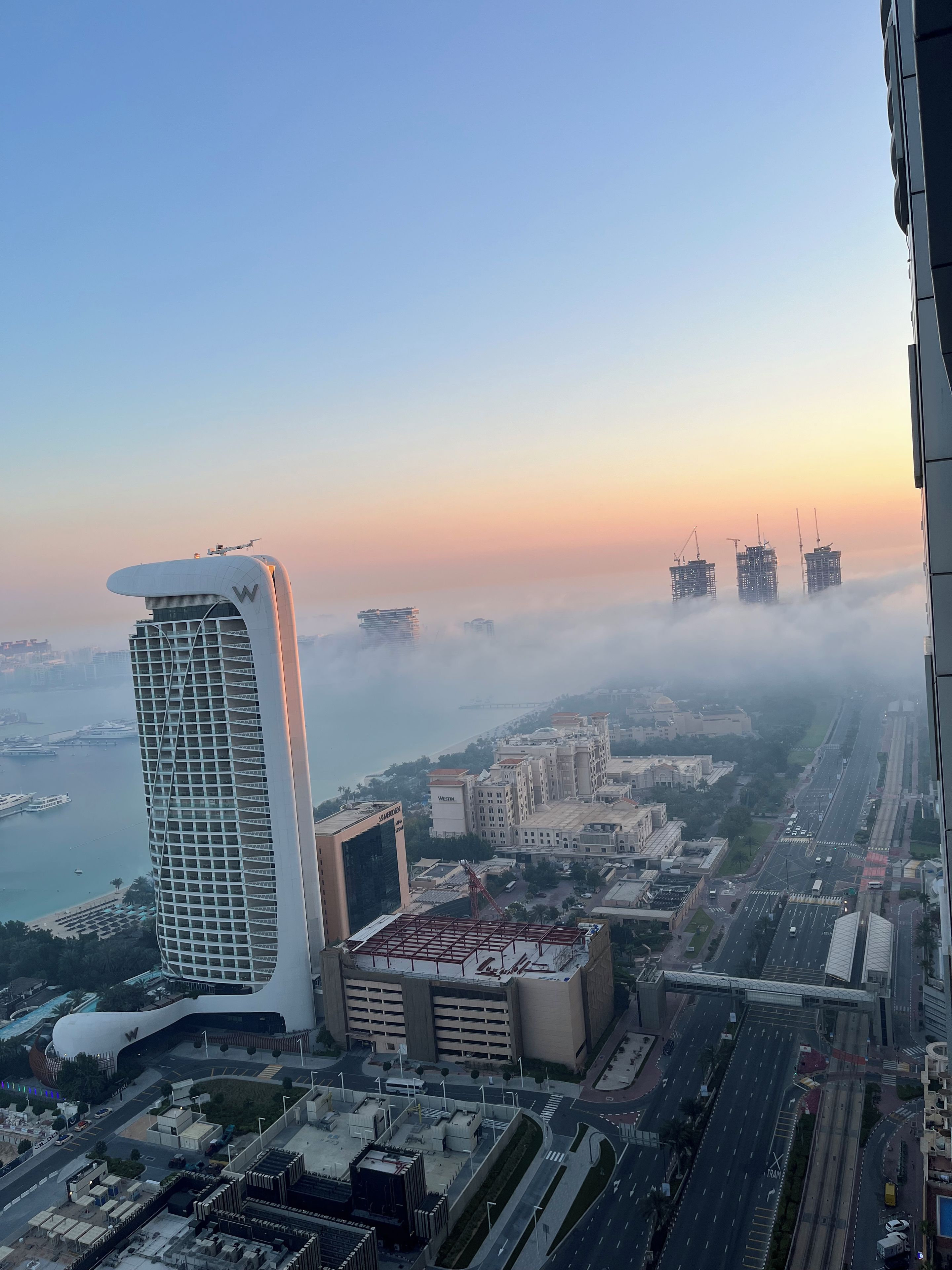 A cityscape with modern buildings, a waterfront, and a clear sky.