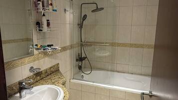 Baño con lavamanos, espejo, ducha e inodoro.