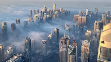 A high-rise urban area with multiple skyscrapers, a body of water, and a dense cloud cover.
