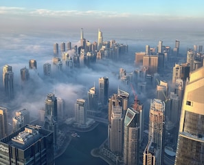 A high-rise urban area with multiple skyscrapers, a body of water, and a dense cloud cover. - PRINCESS TOWER HOUSE MIX DORMITORY (Dubai)