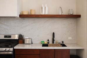 A kitchen with a stainless steel stove, a toaster, and a sink with a black faucet. - Casa Solea | Luxury Eco Villa in Playa Pelada (Nosara)