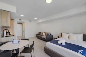 A hotel room with a bed, a sofa, a dining table with chairs, a kitchenette, and a bathroom. - Spacious Miami Condo - Near Brickell (Miami)