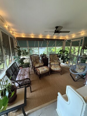 Ein überdachter Patio-Bereich mit Sitzgelegenheiten, Lichterketten und Topfpflanzen.