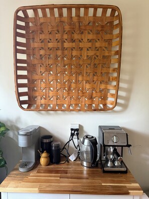 Eine Küchenarbeitsfläche mit einer Kaffeemaschine, einem Wasserkocher und einer Kaffeemühle.