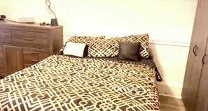 A bedroom with a patterned bedspread, a dresser, and a nightstand. - 3-bedroom house in charming Salisbury with cool AC (Salisbury)
